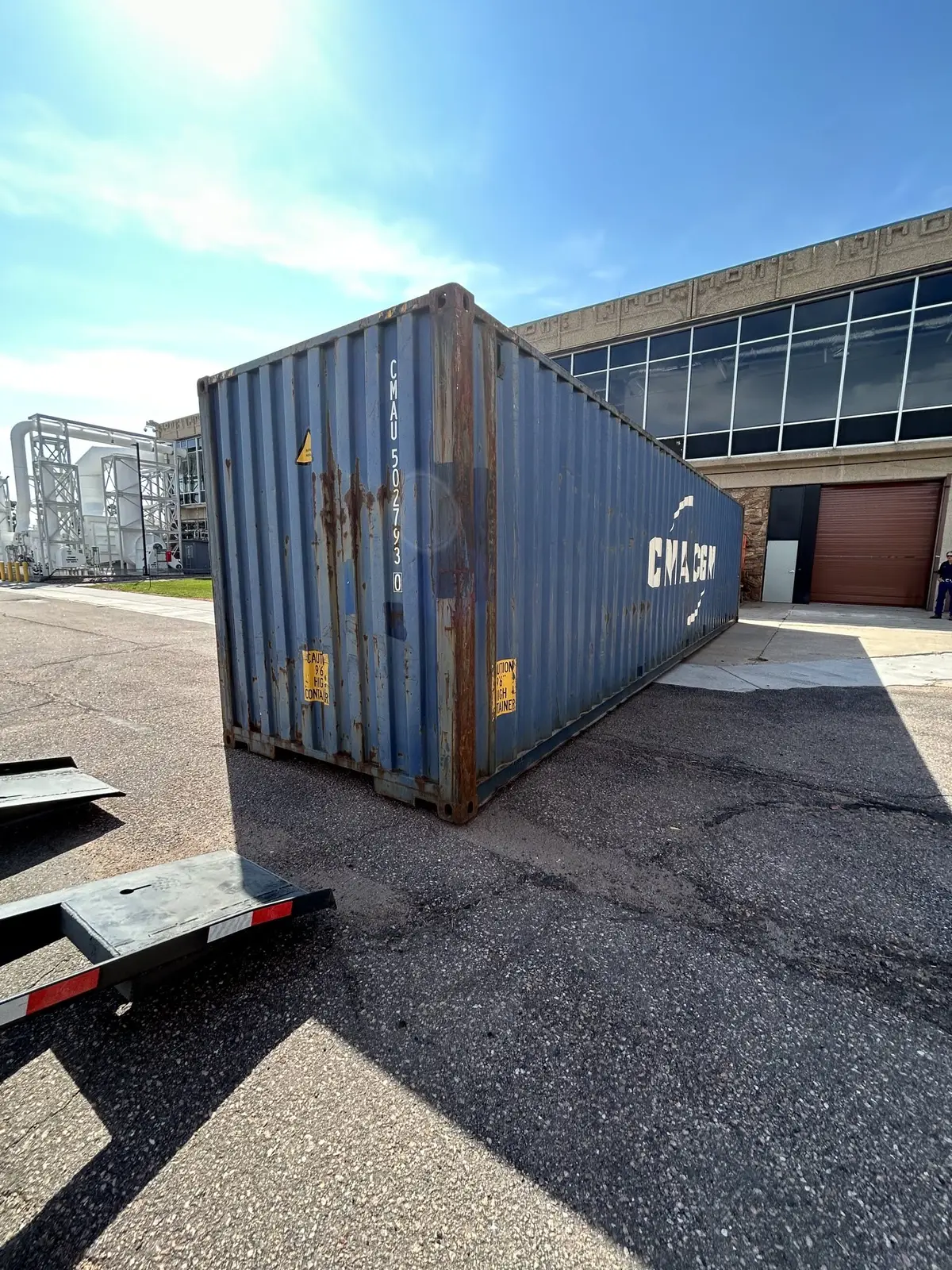 Blue 40-foot shipping container on a trailer outside a commercial building