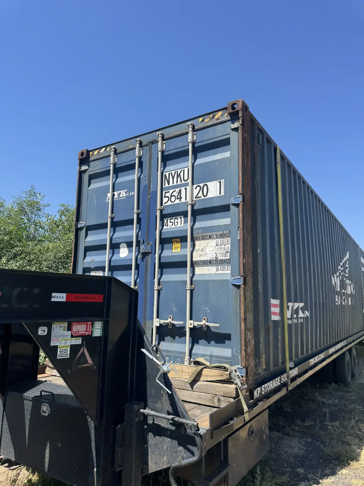 Blue 40-foot shipping container loaded on a gooseneck trailer
