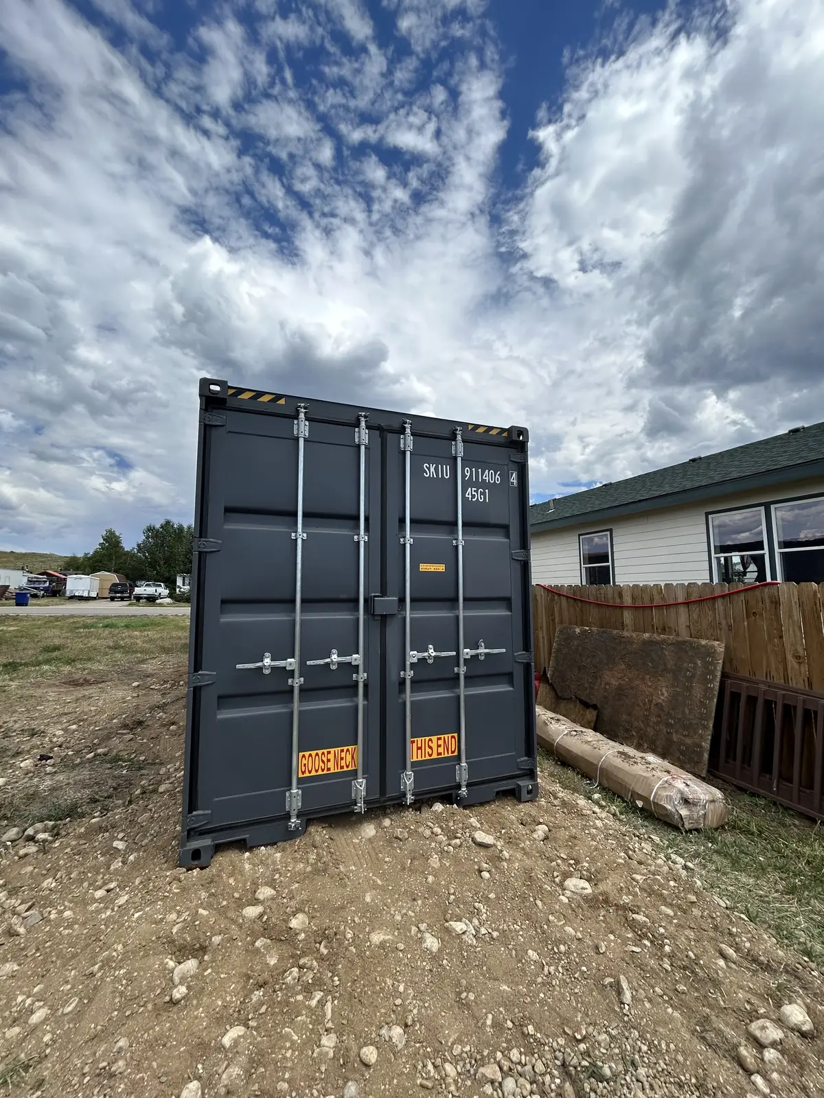 Charcoal shipping container placed on a gravel residential property