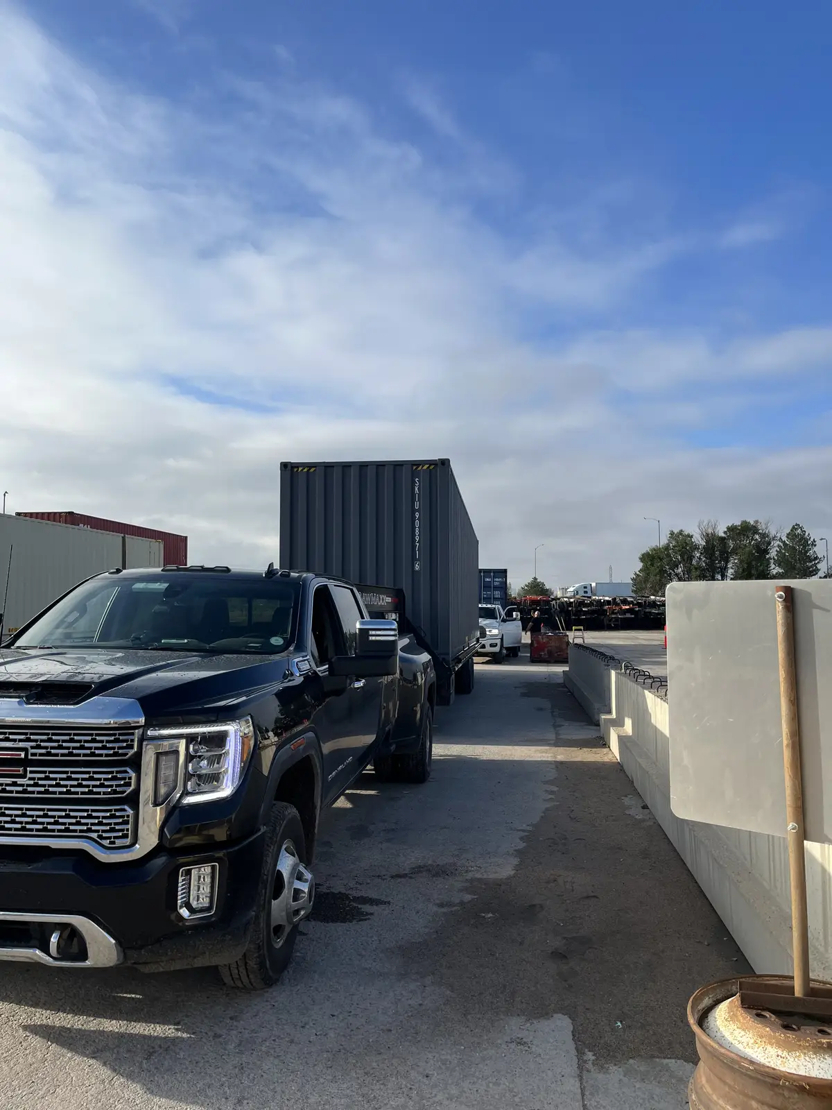 Black pickup truck hauling a tall shipping container on a trailer